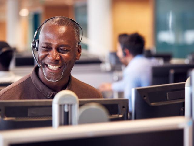 lächelnder Mann mit Headset im Callcenter