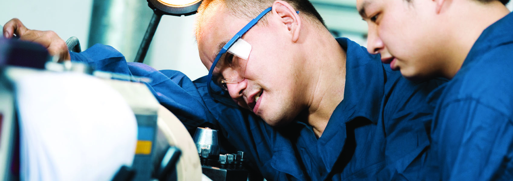 Ingenieur lernt jungen Mann an Maschine an