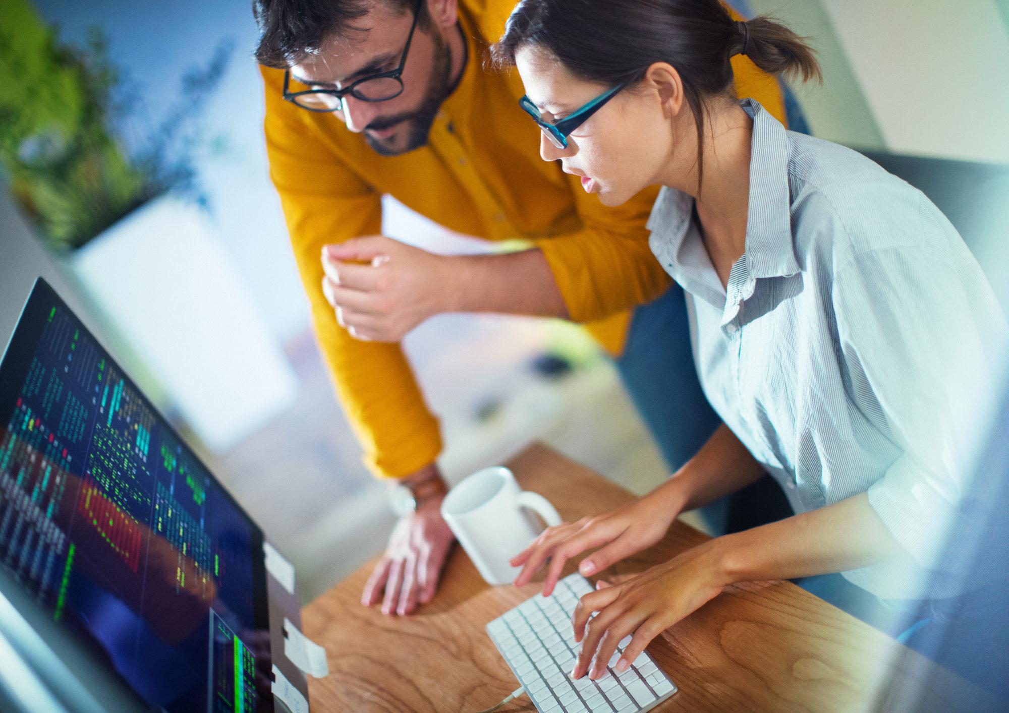 Geschäftsmann, der einen Kollegen an einem Desktop-Computer einweist