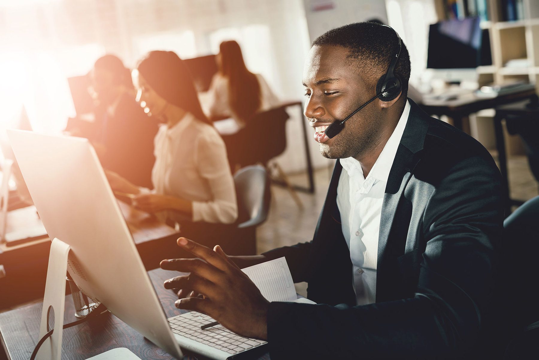 Callcenter-Mitarbeiter arbeitet am Computer und spricht über Headset