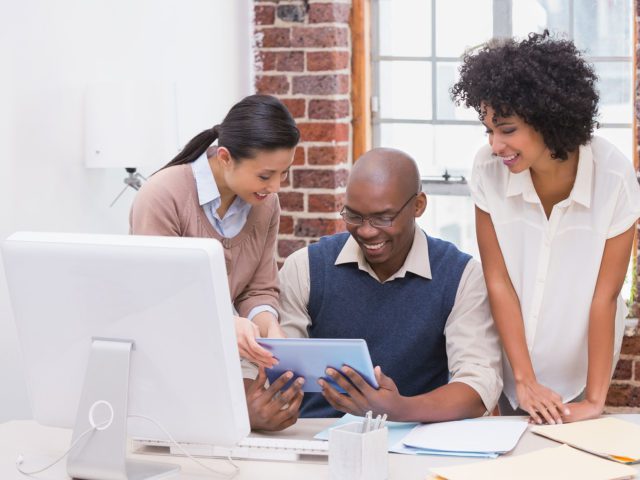 Kollegen arbeiten in einem Büro gemeinsam an einem digitalen Tablet