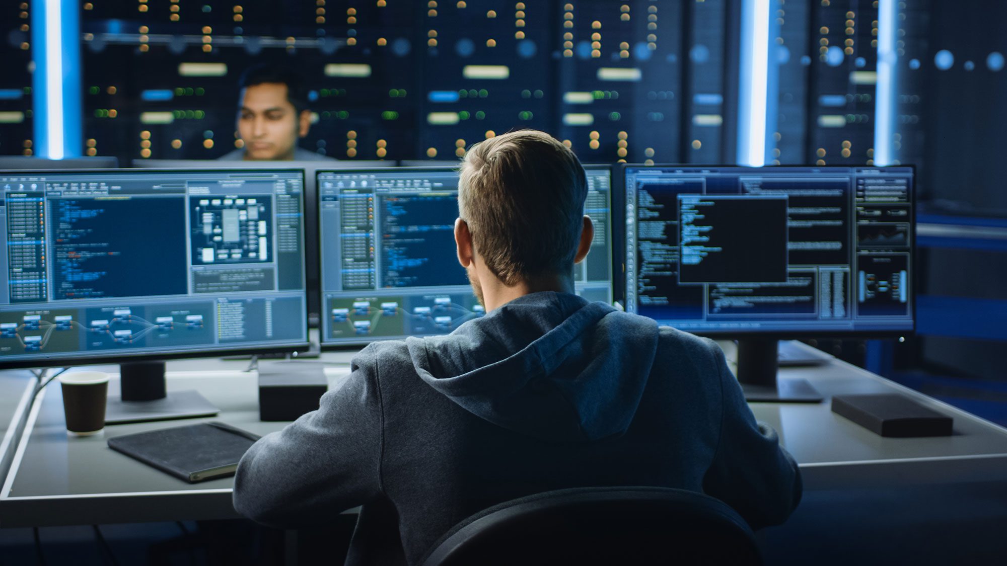 Mann sieht sich Code auf drei Monitoren an
