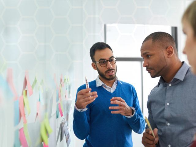 Porträt eines Inders in einem vielfältigen Team kreativer Millennial-Kollegen in einem Startup beim Strategie-Brainstorming