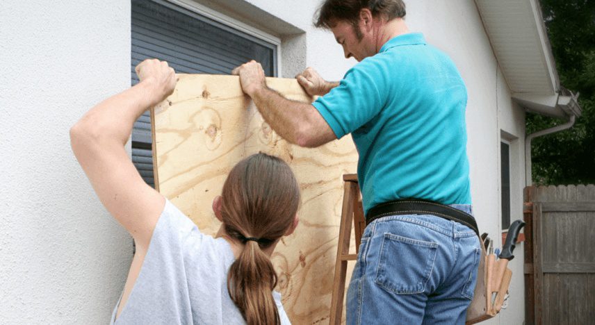 Handwerker und Handwerkerin, die die Fenster eines Hauses mit Holz verschalen